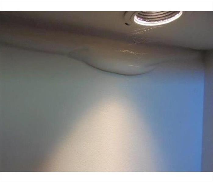 large water blister by ceiling, white wall